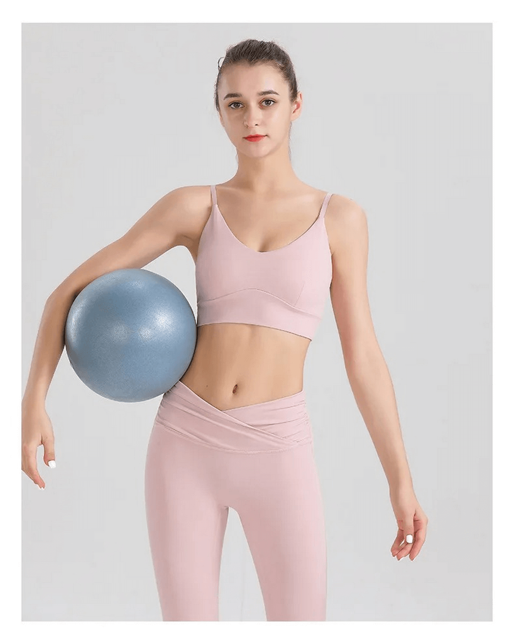Woman in pink spandex workout set holding a fitness ball, showcasing durable and breathable activewear for women. Perfect for yoga or gym sessions.